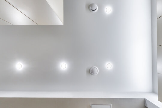 suspended ceiling with halogen spots lamps and drywall construction in empty room in apartment or house. Stretch ceiling white and complex shape.