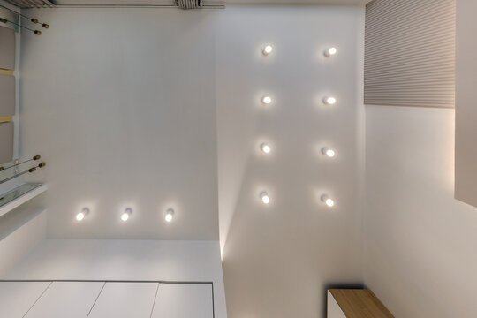 suspended ceiling with halogen spots lamps and drywall construction in empty room in apartment or house. Stretch ceiling white and complex shape.