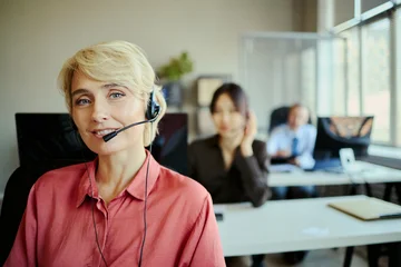 Fototapeten Musik Portrait of smiling Caucasian young adult woman wearing headset and assisting customers in call center office, representing client support and team service for business marketing  © DragonImages