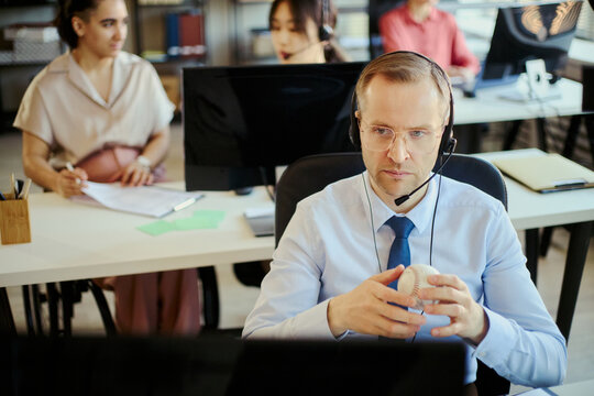 Middle aged Caucasian businessman wearing headset, handling customer support in call center office with team. Suitable for customer service, sales support, CRM marketing