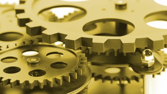 Close up shot of mechanical golden gears and cogs wheels mesh working together. Industrial machinery mechanism, engineering technology, connection concept or business operation system footage.