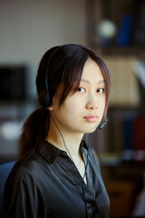 Naklejka premium Portrait of young Asian woman wearing headset, working in call center office and looking at camera, representing customer support and service. For CRM, help desk, outsourcing marketing, vertical