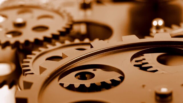 Close up shot of rotating metallic bronze gears and cogs mechanism. Concept of teamwork, industrial engineering, machinery technology, antique clockwork or business operation system.