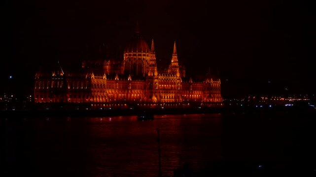 Hungarian parliament building illuminating the danube river at night. Majestic hungarian parliament building brightly illuminated with golden lights, beautifully reflecting on the tranquil waters