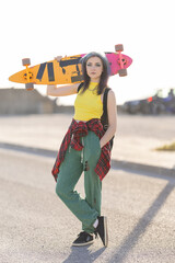 Young woman holding skateboard on shoulder standing outdoors © KONSTANTIN SHISHKIN