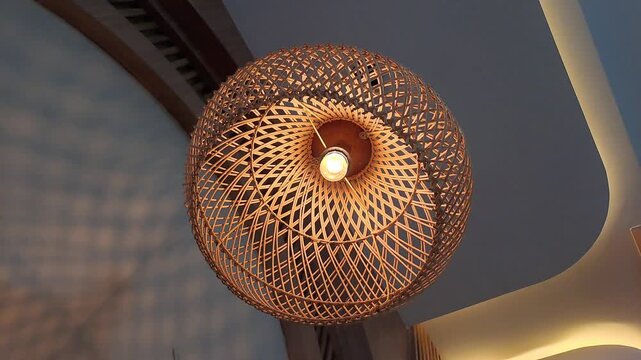 Cinematic footage of a modern minimalist cafe interior featuring an aesthetic rattan pendant light gently swaying. The video showcases warm ambient lighting with hidden LED strips along the ceiling.