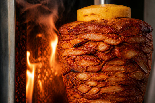 Shawarma meat rotating on vertical spit with pineapple top