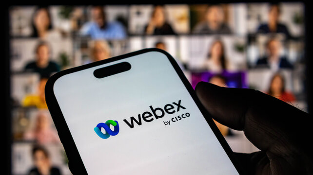 Closeup of a smartphone displaying the webex by cisco logo with a blurred video conference background
