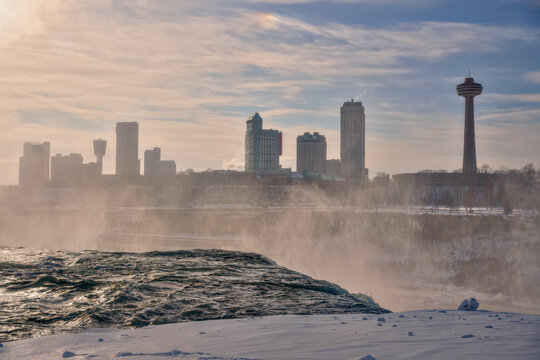 Skylon Tower and Niagara Falls framed by winter mist and snowy shore