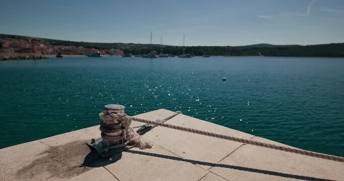 Mooring bollard with rope on a stone waterfront overlooking the Adriatic Sea in Primosten, Croatia.