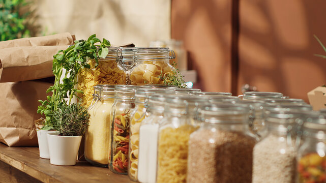 Close-up on bulk food items in reusable glass jars used by zero waste supermarket to lower climate impact, eco friendly local shop pantry staples in decomposable packaging, panning shot.