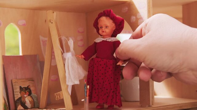 hands of miniature artist arranging dolls and objects in dollhouse, artist doll easel, tiny studio scene, detailed composition, creative hobby, hobby of miniatures handcrafted setup, closeup process