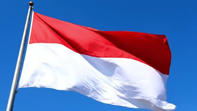 Indonesian national flag waving on flagpole against clear blue sky
