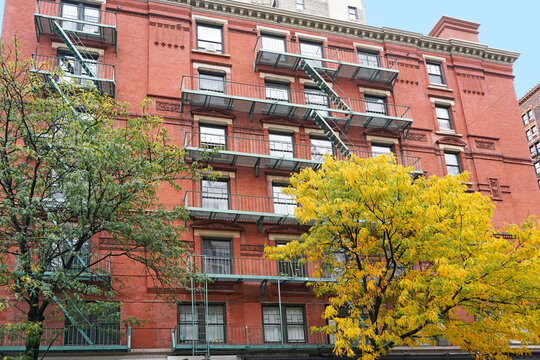 Manhattan apartment building with fire escape and trees in fall