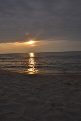 Obraz premium Sunset over tranquil ocean waves with sandy beach foreground 