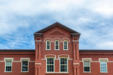 Symmetrical facade of a historic red brick building with arched windows and central gable in Boston, Massachusetts, USA  © Baharlou