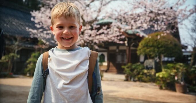Smiling Boy with Backpack In Front Of Cherry Blossom Temple In Hiroshima - Slow, Medium Angle Shot