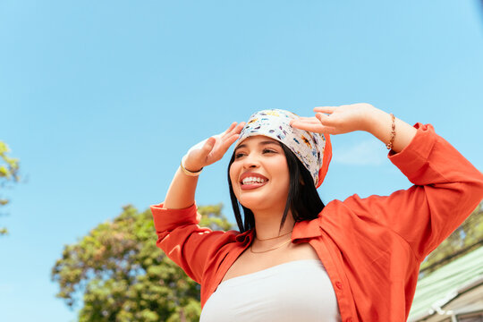 Young woman shielding eyes looking up cheerful day