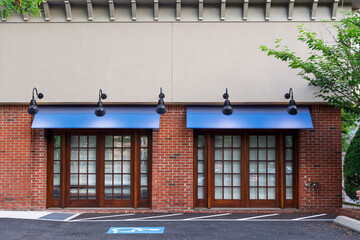 Obraz premium Commercial building facade with blue awnings, brick exterior, and wood framed storefront windows in Brookline, Massachusetts