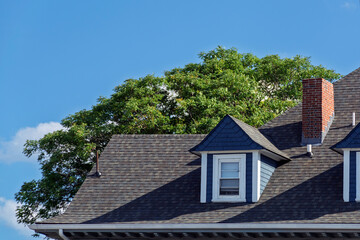 Traditional residential house roof with dark shingles and blue dormer window in Boston  © Baharlou