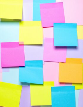 Assorted colorful sticky notes overlapping on a surface. Bright yellow, pink, blue, and orange paper memo squares, office stationery for planning and organizing.