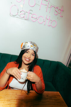 Young woman enjoying coffee inside a cafe with neon sign