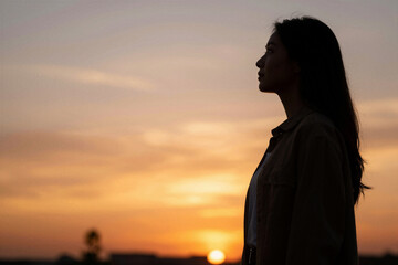 Fototapeta premium Woman silhouette gazing at sunset over distant horizon