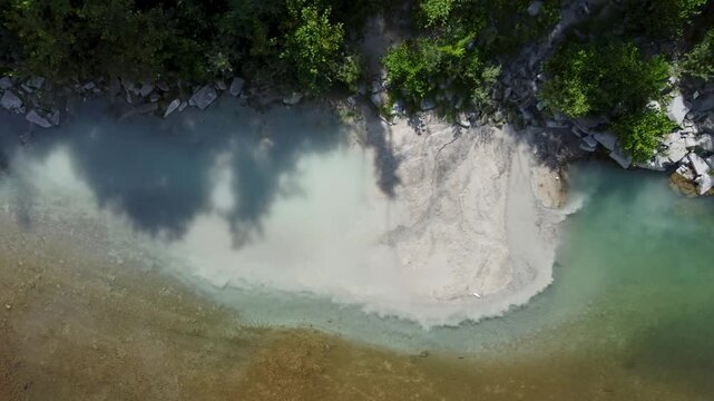 Sewage discharge flowing into a clean river aerial drone view. Wastewater entering river. Pollution from sewage pipe flowing into clean river from above.