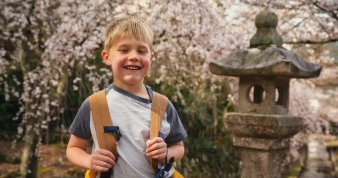 Smiling Boy with Backpack by Stone Lantern And Spring Cherry Blossoms In Hiroshima