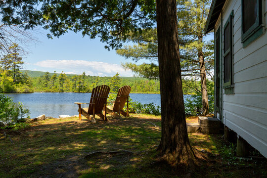 Scenic Maine lakefront cabin with two Adirondack chairs out front. 