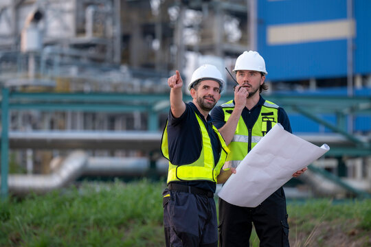 Engineers planning industrial project holding blueprint and radio