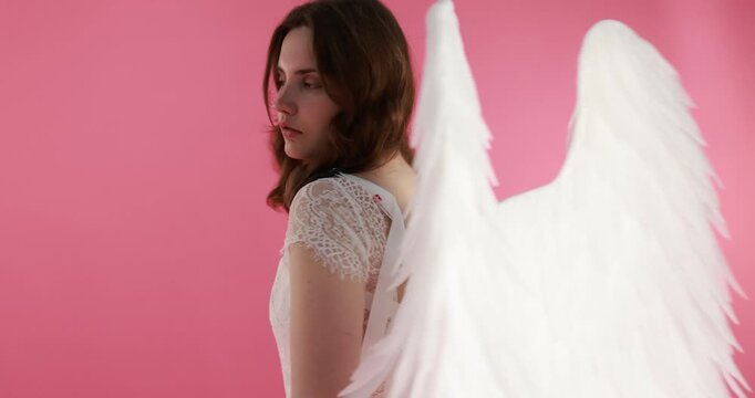Beautiful girl with angel wings on pink background