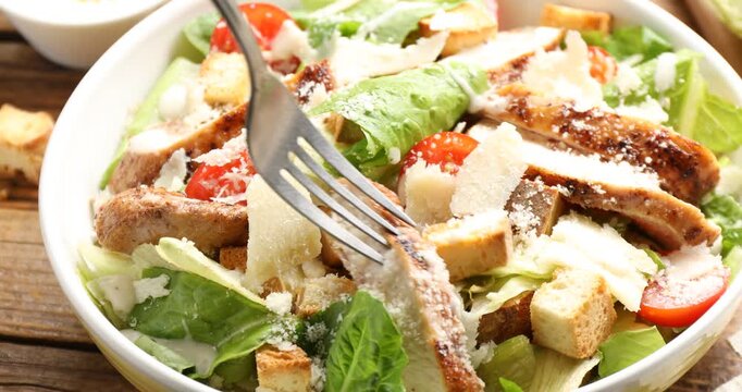 Woman eating tasty Caesar salad at wooden table, closeup