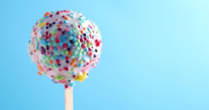 One tasty cake pop spinning on light blue background, closeup