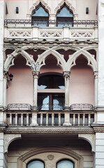Naklejka premium Balcony and windows on the white faзade of a neoclassical building with oriental relief motifs, capitals, and decorative elements. Lviv, Ukraine.