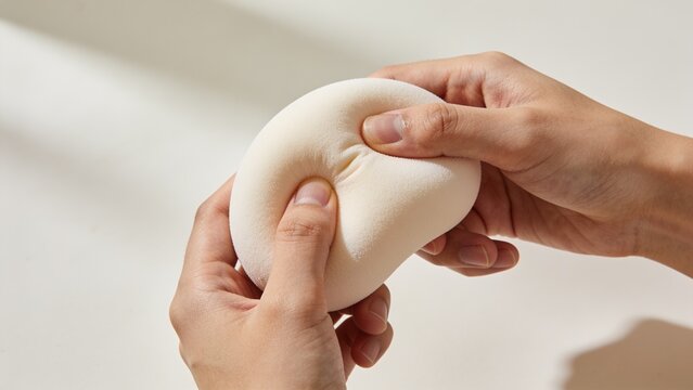 Hands squeezing soft white anti stress squishy toy for anxiety and pressure relief