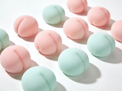 Peach shaped pastel pink and green squishy mochi anti stress fidget toys on white background