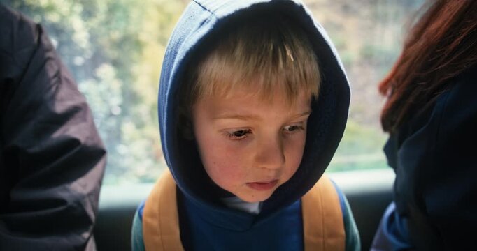 Closeup Of Young Child in Blue Hoodie Seated Inside Moving Gondola In Japan