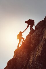 Naklejka premium Explore adventure outdoor in National Park. Two climbers silhouetted against the setting sun, climbing a rocky outcrop. The sky is painted in a gradient of orange and pink hues.