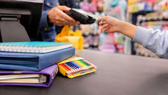 School supplies on checkout counter with customer hands