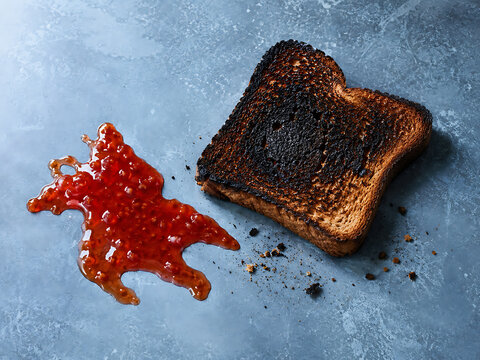 Single piece of burened brade or burnt toast with bright red fruit sauce on blue table breakfast bureaued culinary minimalist delicious textured gastronomy nutrition