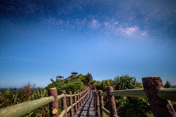 Scenic path and walking trail on a hill under the beautiful Milky Way galaxy and starry night sky. © YouXiang