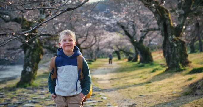 Child with Backpack Smiling Among Cherry Blossom Trees In Hiroshima, Japan - Slow Motion Medium Shot