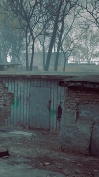 An old brick wall with faded colors is seen in an abandoned place. Nearby, trees are visible in the background. The setting appears to be quiet and deserted.