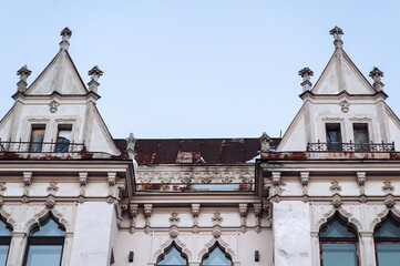 Naklejka premium Antique ornate windows and roof on the white faзade of a neoclassical building with oriental relief motifs, capitals, and decorative elements. Lviv, Ukraine.