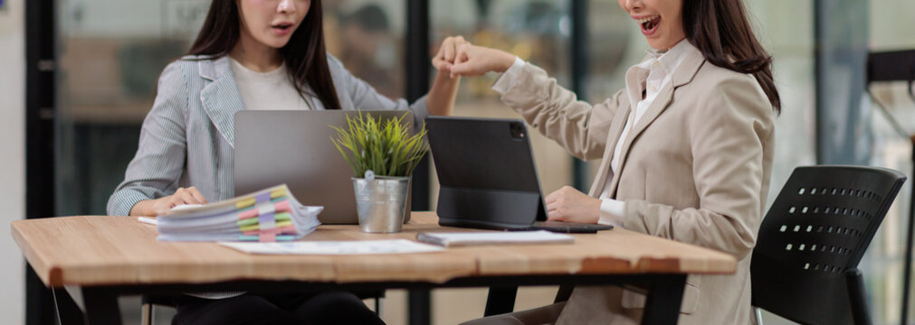 Business women achieving a successful milestone, celebrating teamwork and collaboration with a fist bump gesture after finishing a project at the modern office workspace