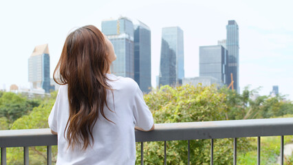 Fototapeta premium Asian Woman Looking at Bangkok City Skyline from Benchakitti Park Bridge
