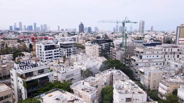 Drone circles Tel Aviv, two cranes dominating the skyline above a dust cloud.