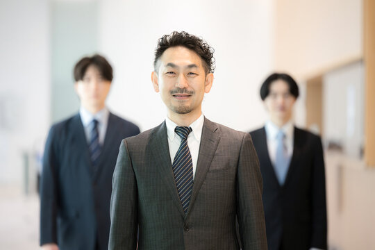 A male business team&mdash;comprising experienced managers, fellow executives, and company presidents&mdash;posing for the camera, along with professionals such as licensed practitioners and consultants　
