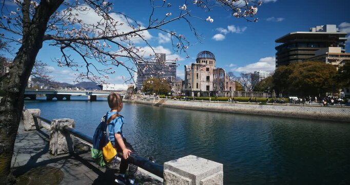 Child Views Hiroshima Peace Memorial Dome Across River in Spring Season - Slow Motion